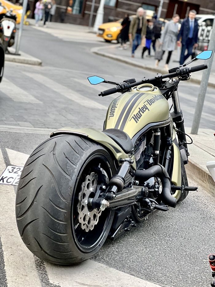 the motorcycle is parked on the side of the road in front of some cars and people