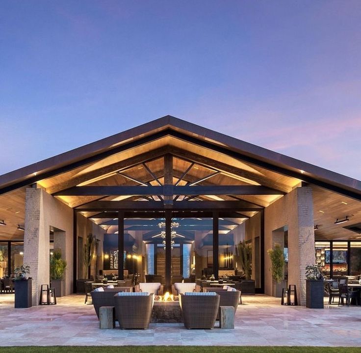 an outdoor dining area with tables and chairs under a lit up roof at night time