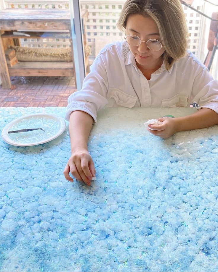 a woman sitting at a table in front of a blue rug with bubbles on it