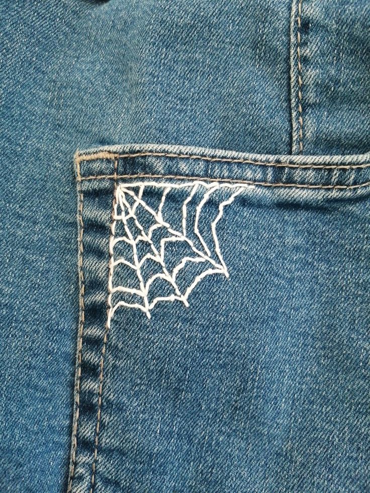 A white spider web embroidery on blue jeans pocket Embroidery On Jeans Tutorials, Jean Pants Embroidery Ideas, Jean Patches Ideas Embroidery, Fashion Design Embroidery, Embroider Spider Web, Embroidery Design On Jeans, How To Embroider Spider Web, Cool Embroidery Designs On Jeans, Embroidery Patterns Pants