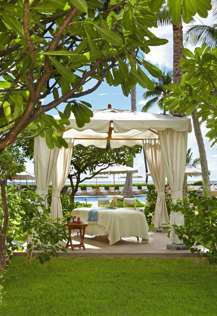 a gazebo in the middle of a lush green yard with trees and chairs around it