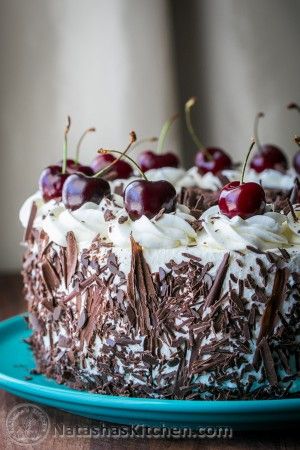 a cake with chocolate frosting and cherries on top is sitting on a blue plate