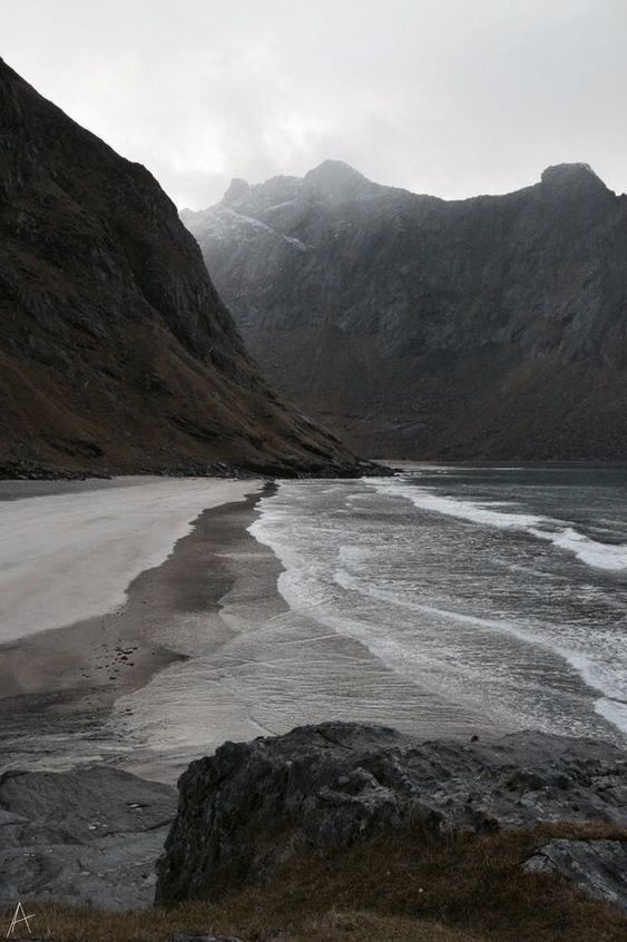 an empty beach with mountains in the background and water flowing from it's sides