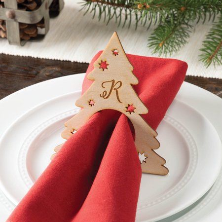 a wooden christmas tree decoration on top of a red napkin with a monogrammed letter