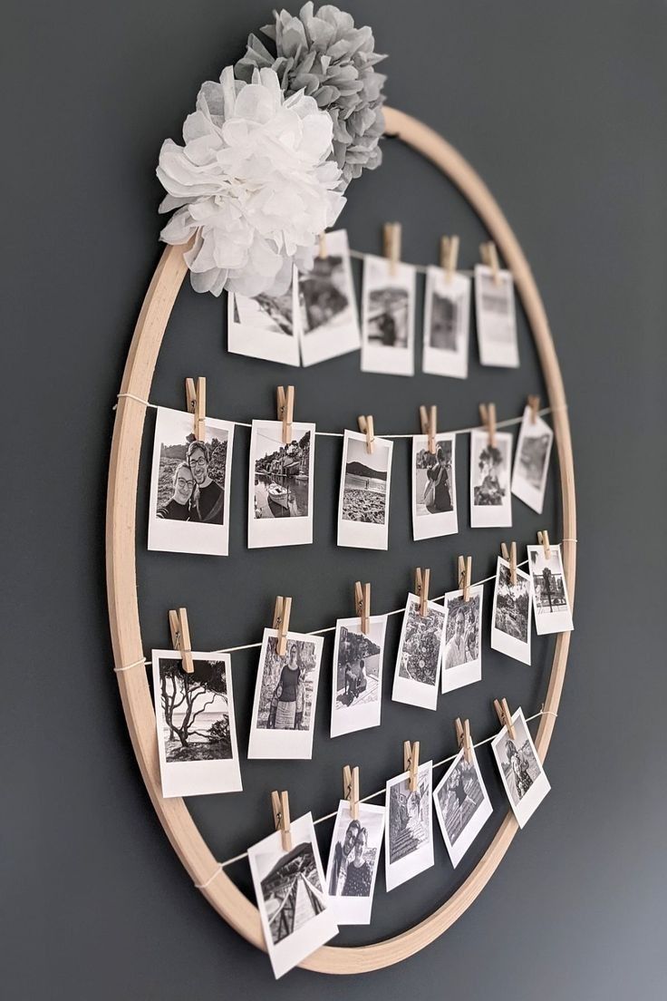 a wooden circle with pictures hanging on clothes pegs and a white flower in the center