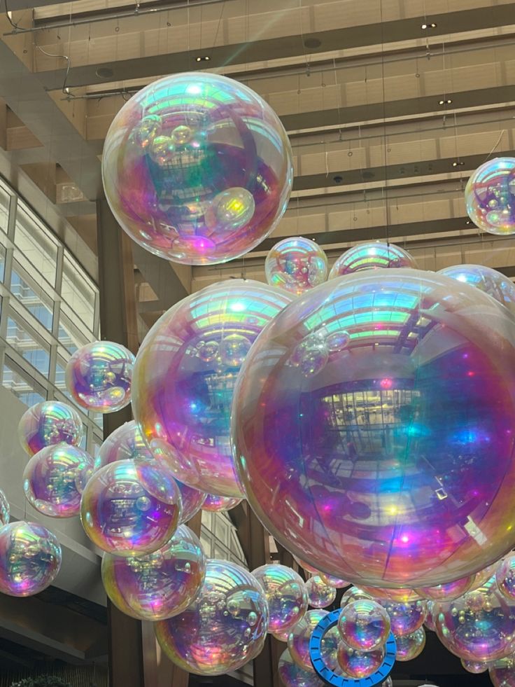 several large bubbles floating in the air near a building's entrance and lobby ceiling