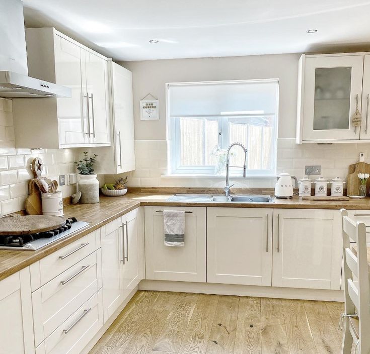 a kitchen with white cabinets and wooden floors