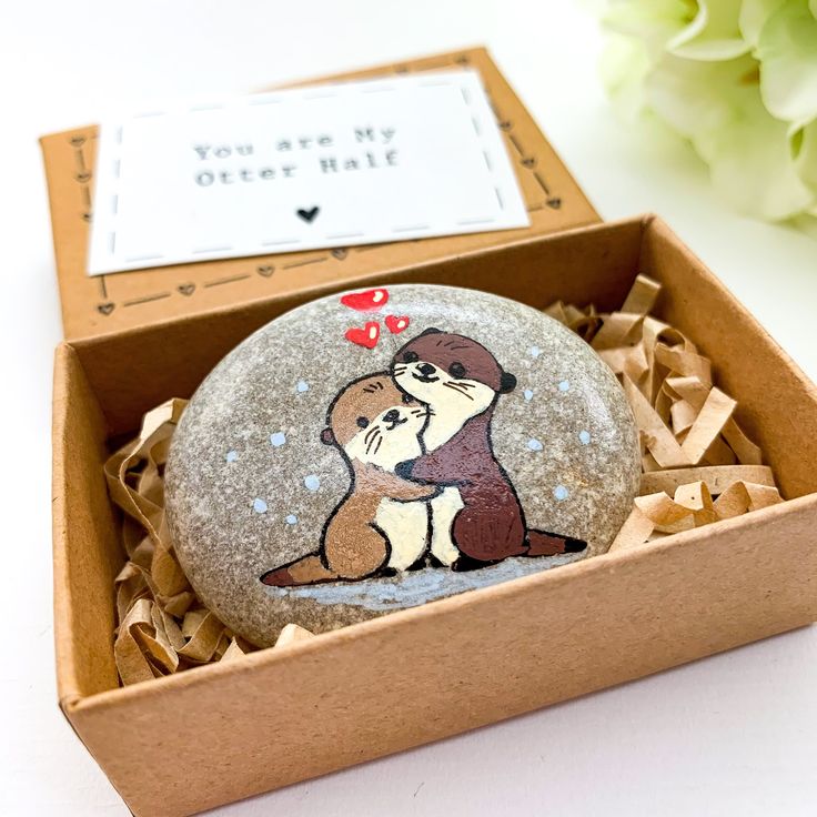 a rock with an image of two otters on it sitting in a cardboard box