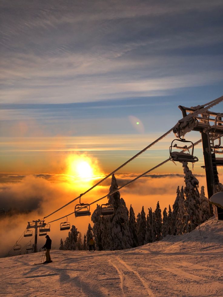 a person on skis standing at the top of a mountain with a chair lift in the background