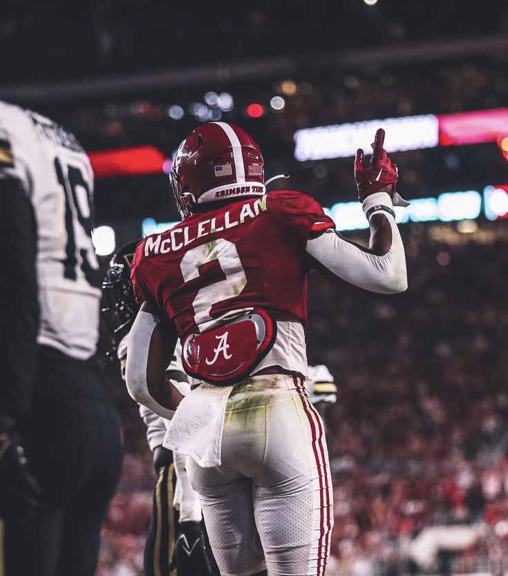 a football player is walking off the field with his hand in the air and another person standing behind him