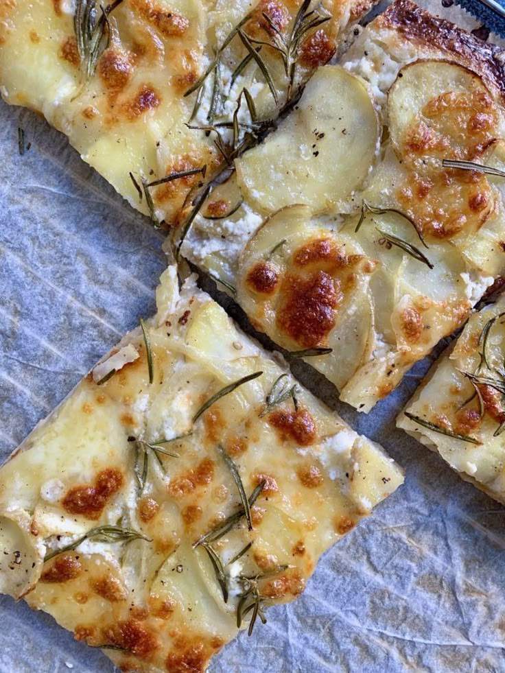 four slices of pizza sitting on top of a piece of wax paper covered in herbs