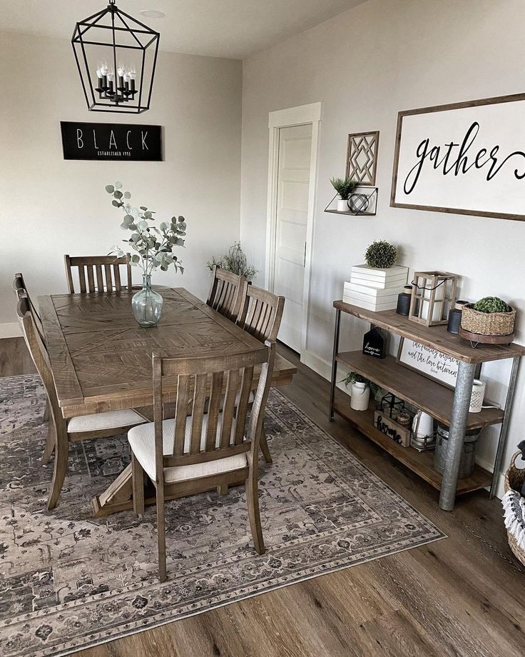 a dining room table and chairs in front of a black sign on the wall above it