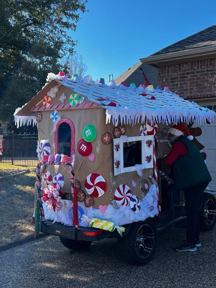 a man standing in the back of a truck decorated like a gingerbread house