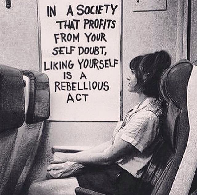 a black and white photo of a woman sitting in a chair with a sign on the wall behind her