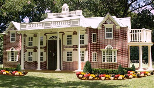 a red and white house with flowers in the front yard