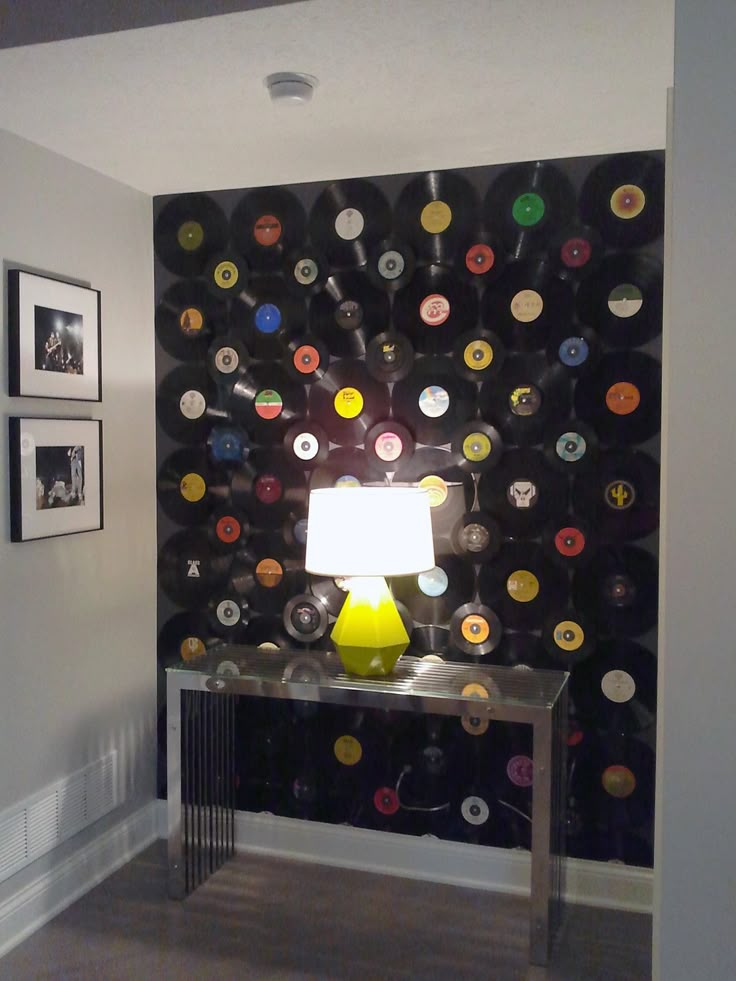 a table with a lamp on top of it in front of a wall full of records