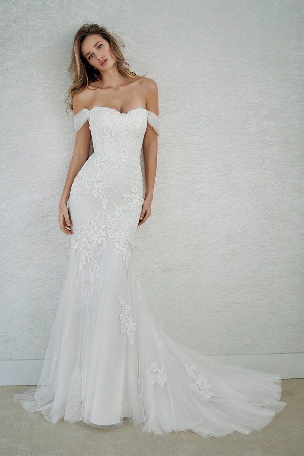 a woman in a white wedding dress posing for the camera with her hand on her hip