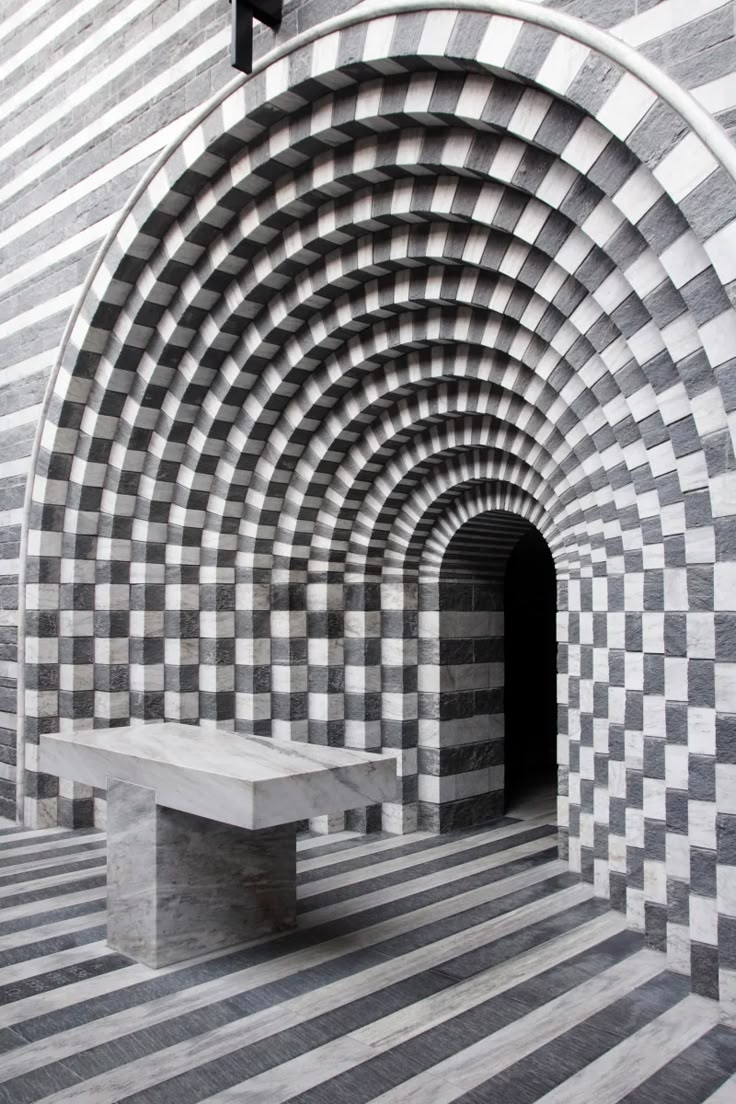 a bench sitting in the middle of a tunnel with black and white checkered walls