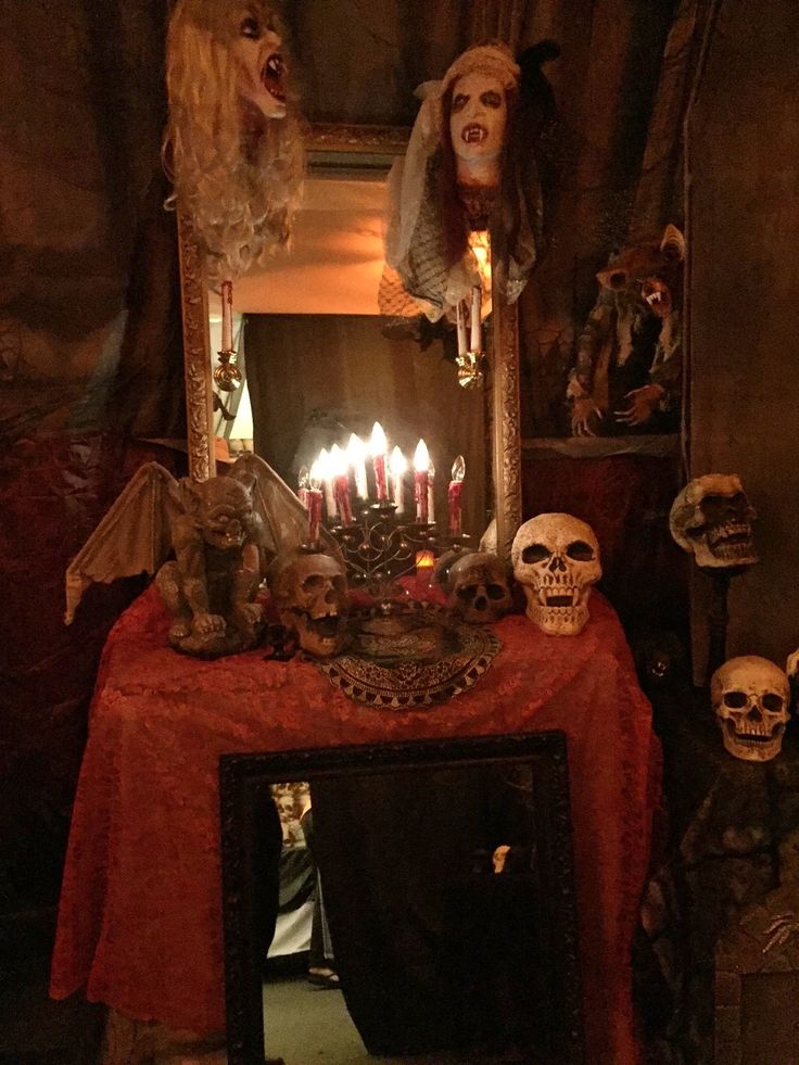 a table topped with skulls and candles in front of a mirror