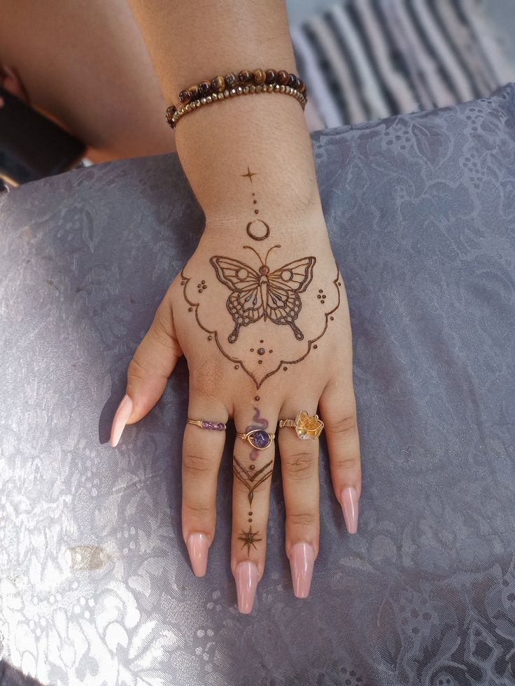 a woman's hand with hendix and butterfly tattoos on it, sitting on a chair