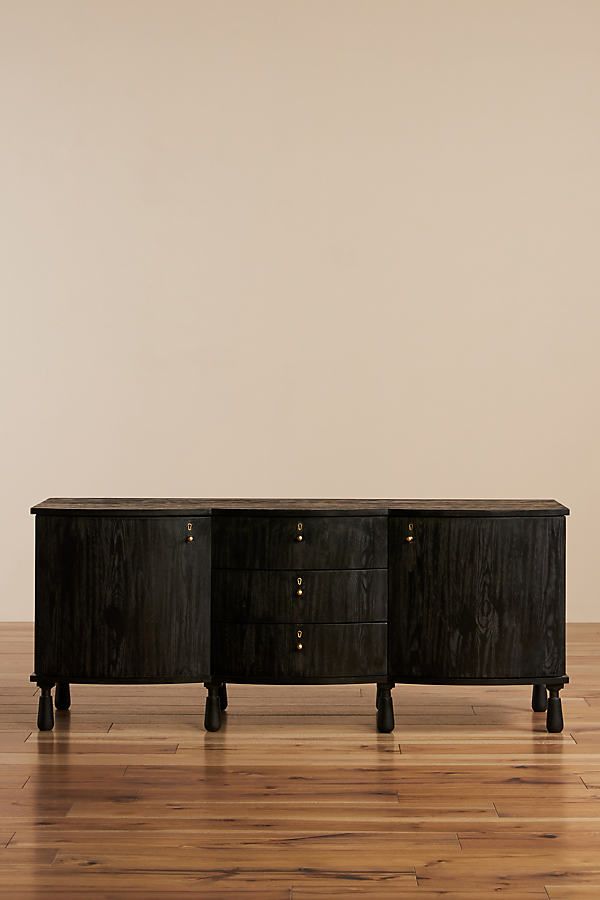 two black dressers sitting on top of a hard wood floor next to a white wall