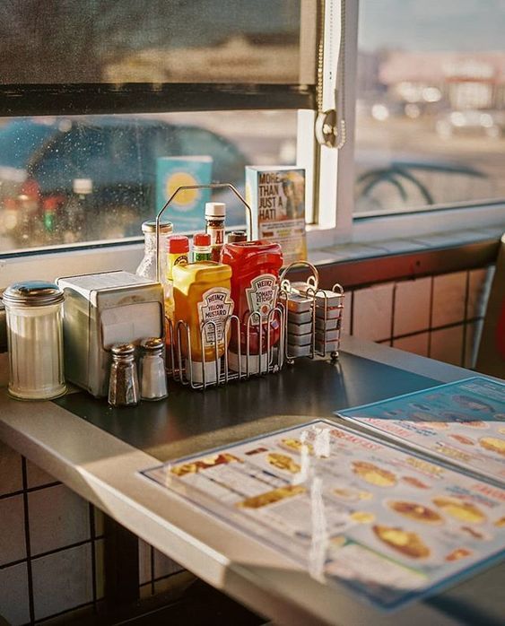 some drinks and condiments sitting on a table in a diner's booth