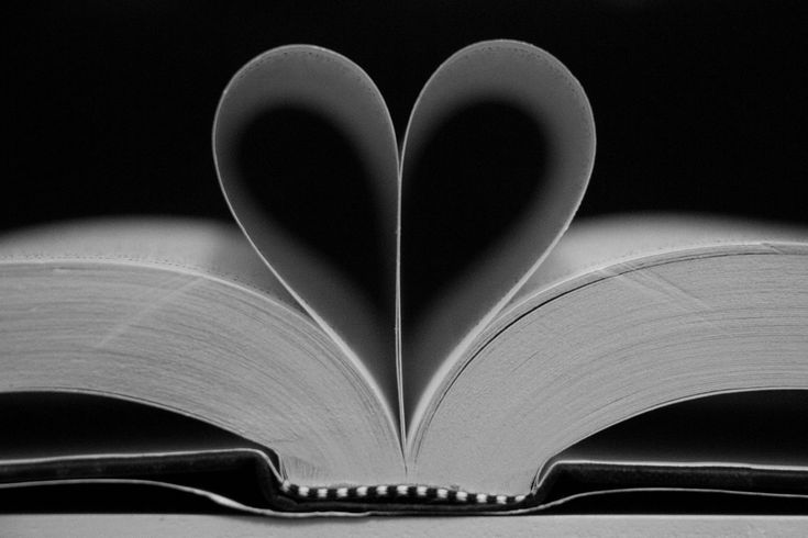 an open book with two pages in the shape of a heart on top of it