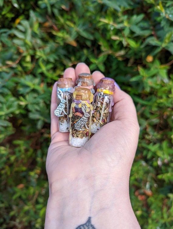 a hand holding several small bottles in it's palm, with tattoos on the arm