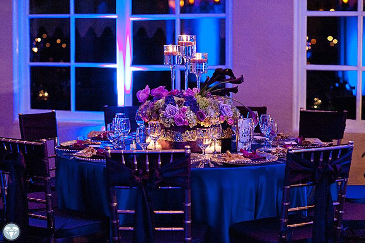 the table is set with purple flowers and candles for an elegant dinner or party event