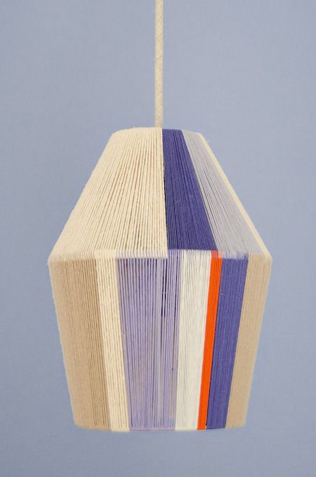 a multicolored lamp hanging from a string on a blue background with an orange, purple, and white stripe