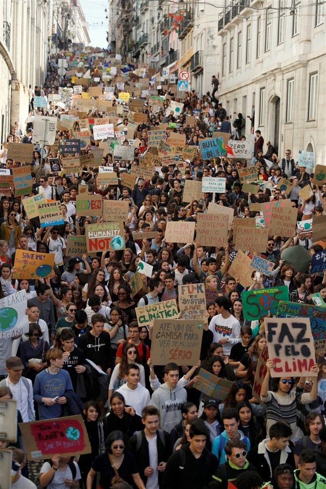 a large group of people walking down a street holding signs