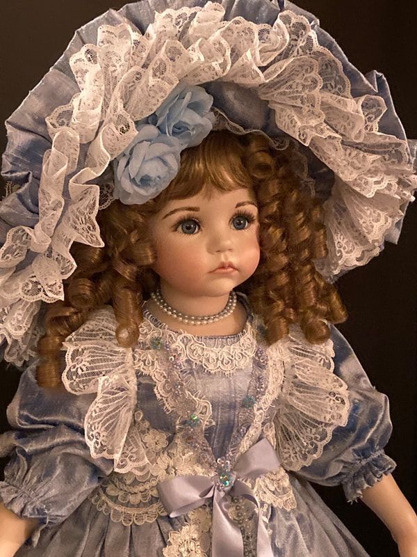 the doll is wearing a blue dress and bonnet