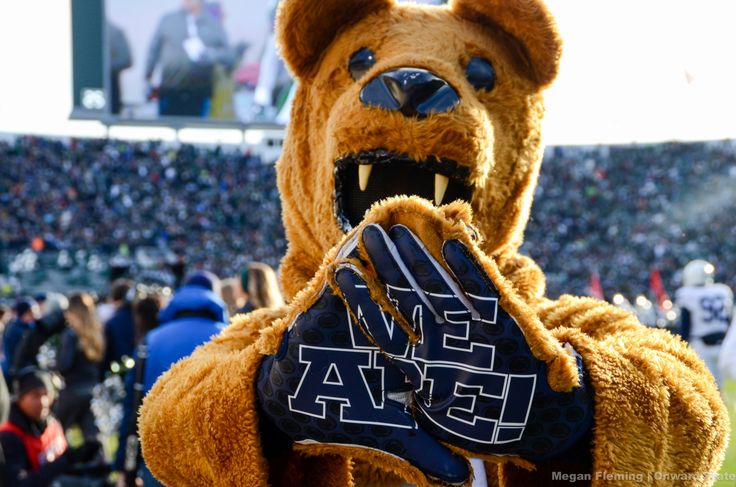 a person in a brown bear costume holding up a glove with the letters ega on it