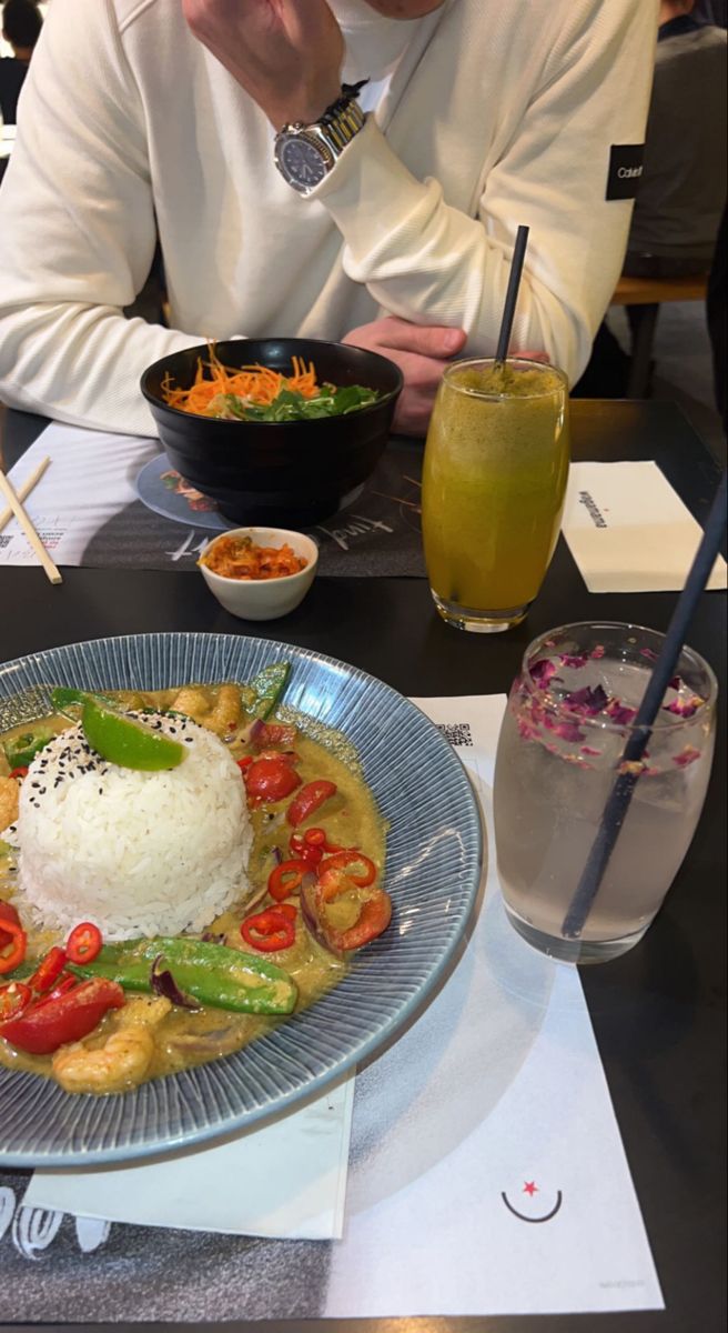 a man sitting at a table in front of a plate of food with rice and vegetables