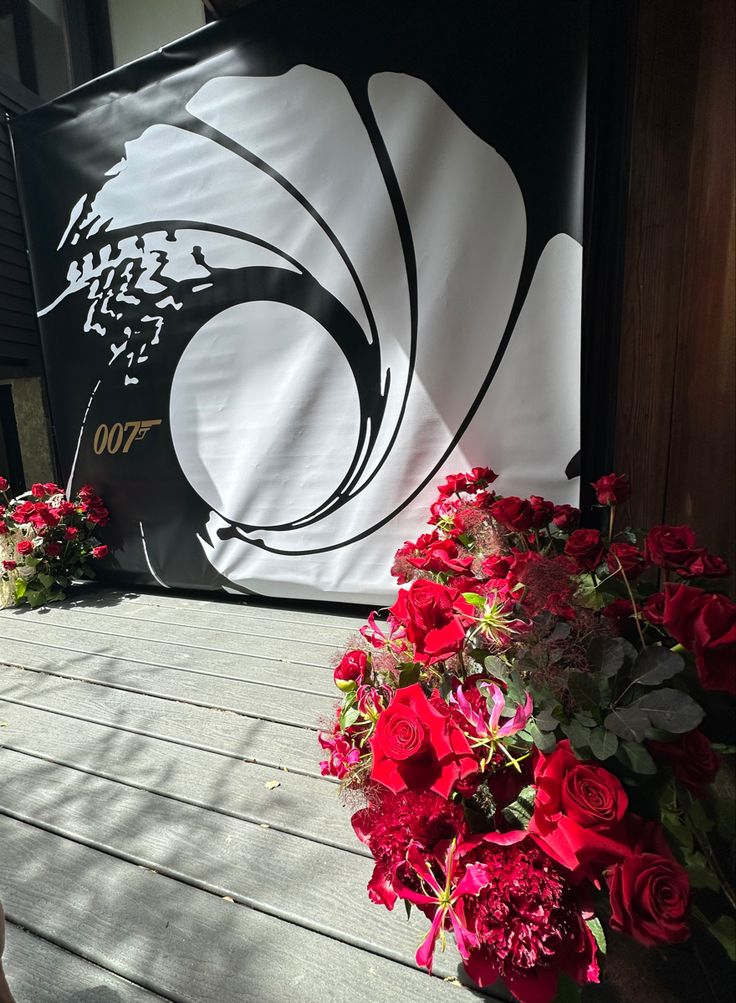 red flowers sitting on the ground in front of a black and white sign that says 00