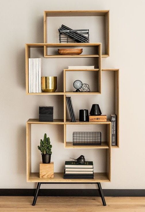 a wooden shelf with books and other items on it against a white wall in an empty room