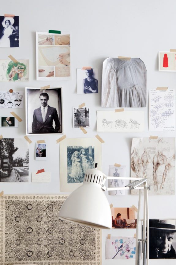 a white lamp sitting on top of a table next to a wall covered in pictures