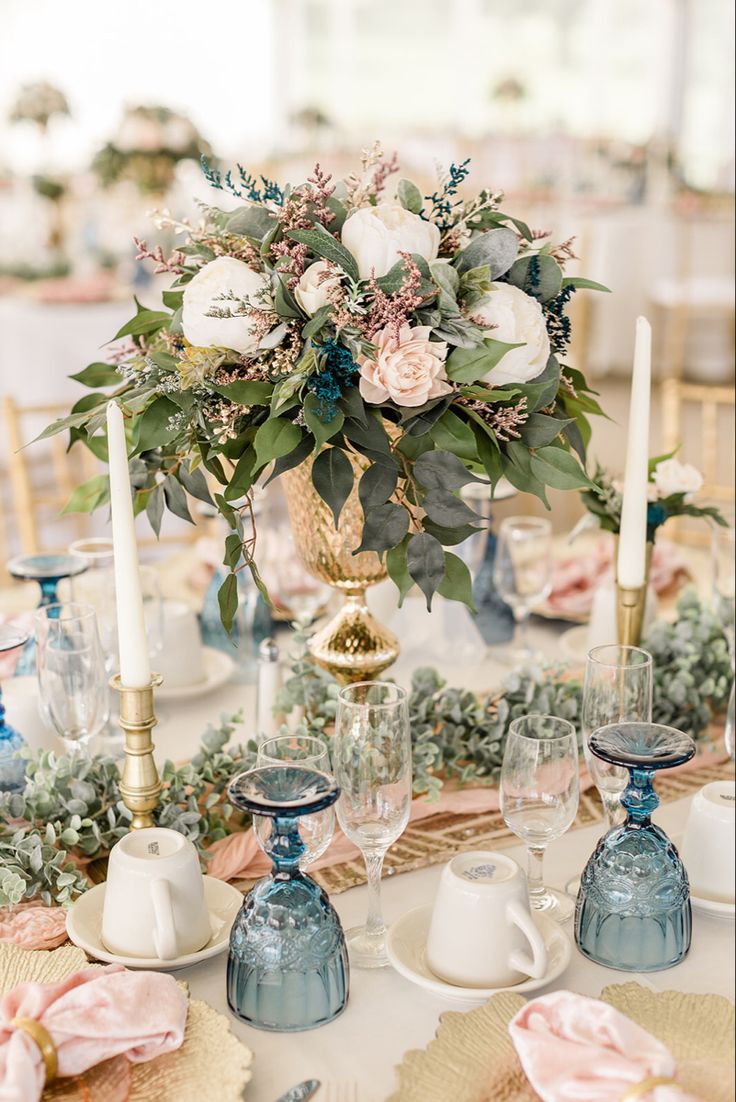 the table is set with blue and white dishes, candles, and flowers in vases