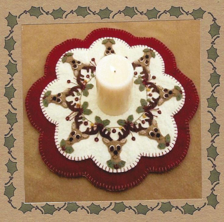 a white candle sitting on top of a red and white doily with deer around it