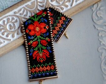 a pair of beaded earrings hanging from a wooden frame