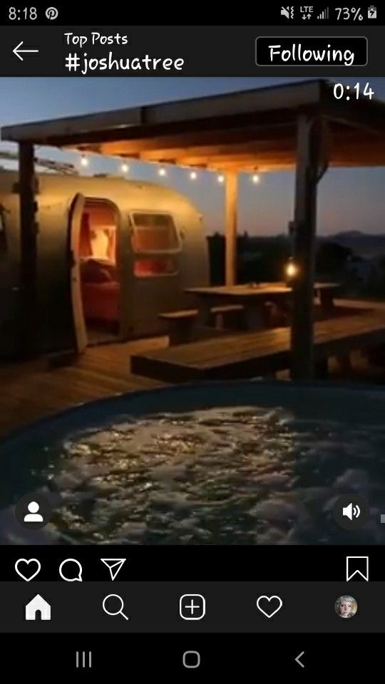 a hot tub sitting under a wooden roof next to a building with lights on it