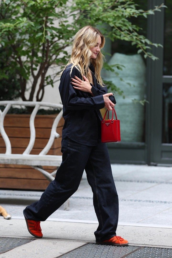 a woman walking down the street carrying a red purse