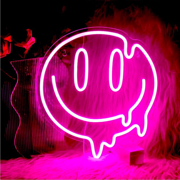 a pink neon sign with a smiley face on it in front of a black background