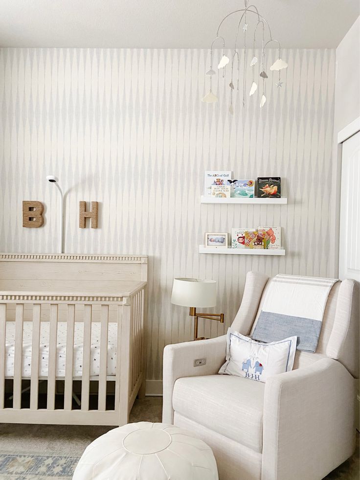 a baby's room with a white crib, chair and ottoman in it