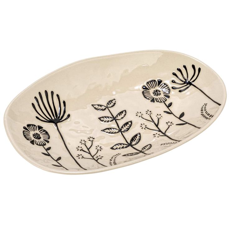 an oval dish with black and white flowers painted on it's side, in the shape of a flower