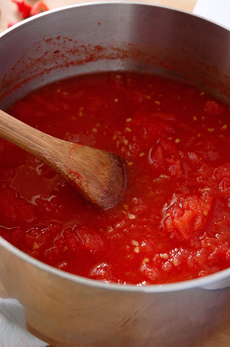 a pot filled with red sauce and a wooden spoon