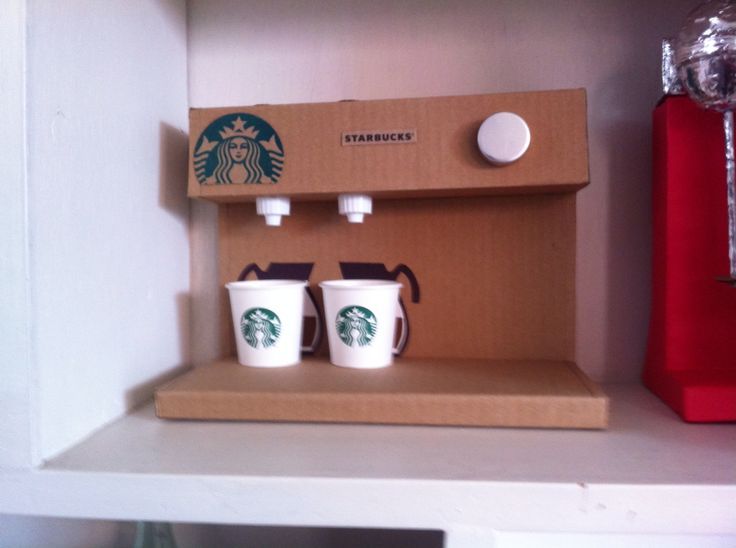 two starbucks cups are sitting on a shelf next to a red coffee cup and a brown box