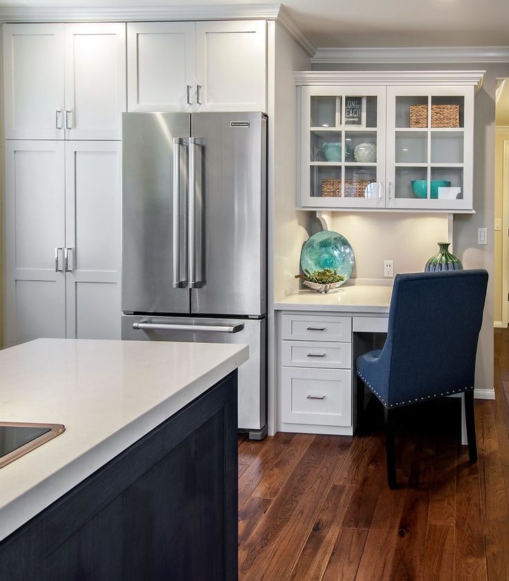 a kitchen with white cabinets and stainless steel appliances, along with a blue chair in the center