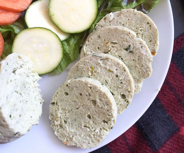 a white plate topped with meat and veggies next to cucumber slices