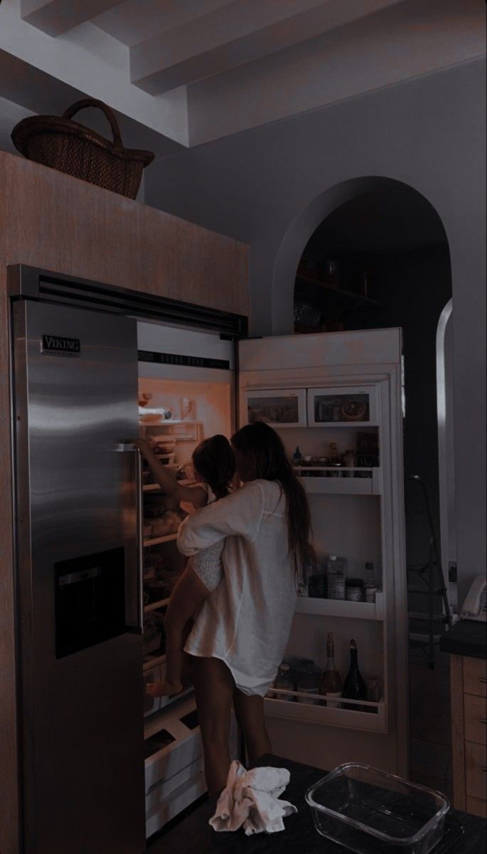 a woman standing in front of an open refrigerator